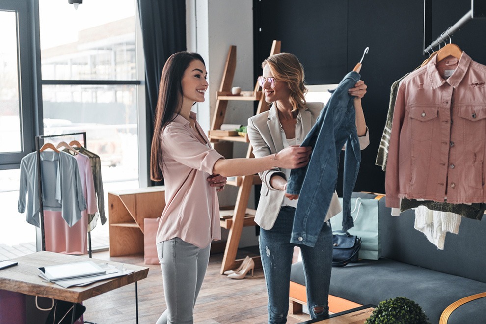 Two women are holding a pair of jeans.