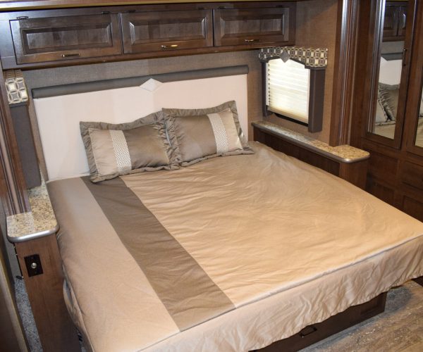 A bed with a white and brown comforter on it.