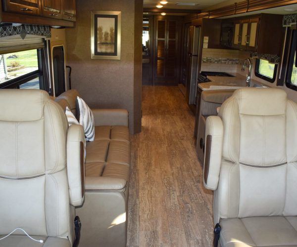 A large motorhome with two seats and a kitchen.