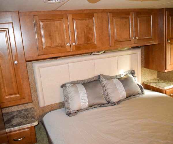 A bed with pillows and headboard in the middle of a room.