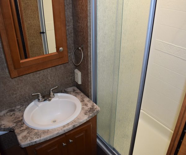 A bathroom with a sink, mirror and shower.