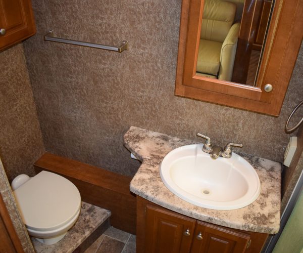 A bathroom with a toilet, sink and mirror.