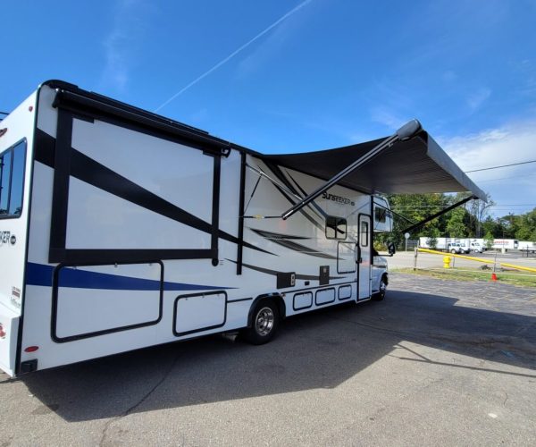 A white and blue rv parked in the parking lot.