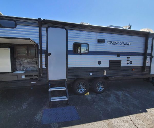 A white and black trailer with a ramp on the side.