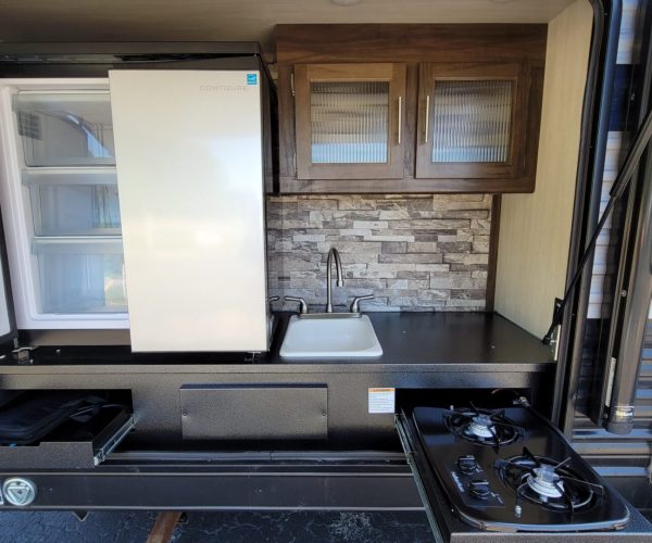 A kitchen with an oven, refrigerator and sink.