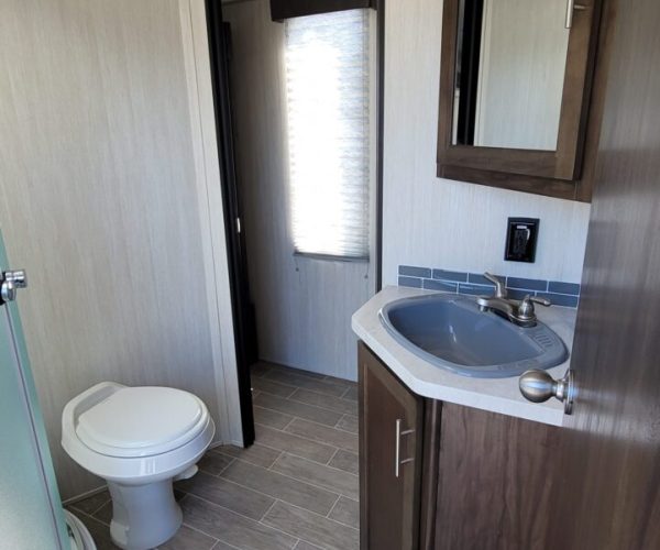 A bathroom with a toilet, sink and mirror.