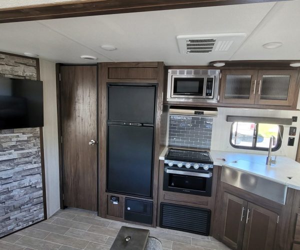 A kitchen with brown cabinets and black appliances.