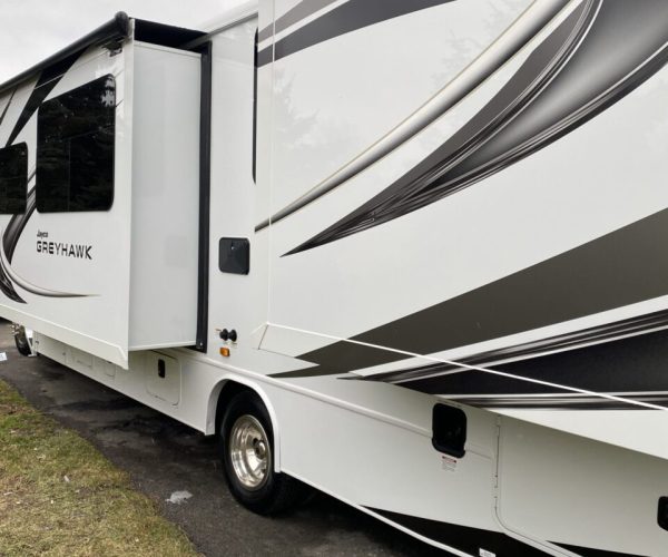 A white and black rv parked on the side of road.