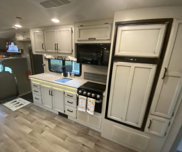 A kitchen with white cabinets and black trim.