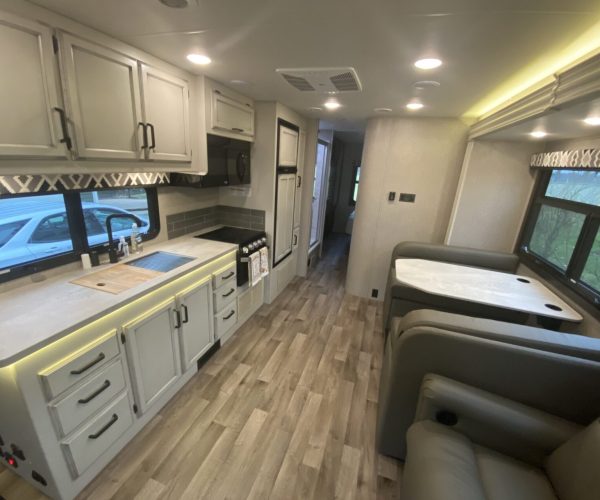 A kitchen with white cabinets and wood floors.