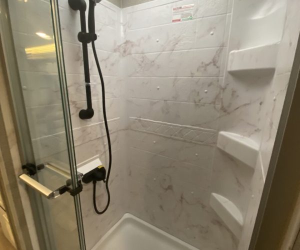 A shower with marble walls and white tile.