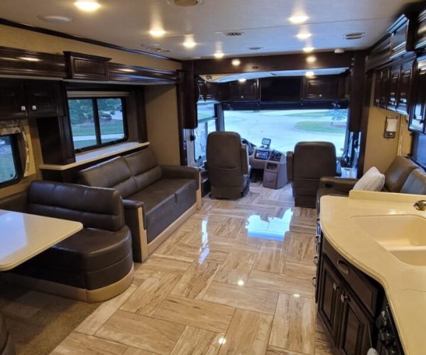 A living room with a couch, television and sink.