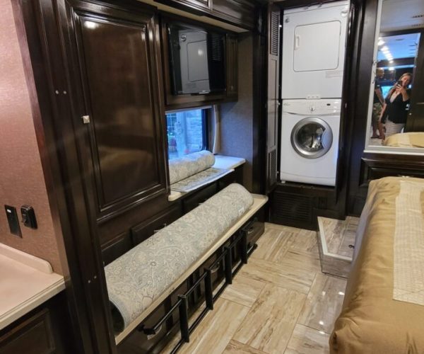 A bedroom with a sink, mirror and a washer.