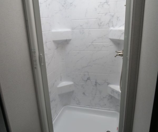 A white shower stall with marble walls and floor.