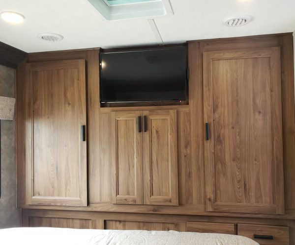 A bedroom with wooden cabinets and a flat screen tv.