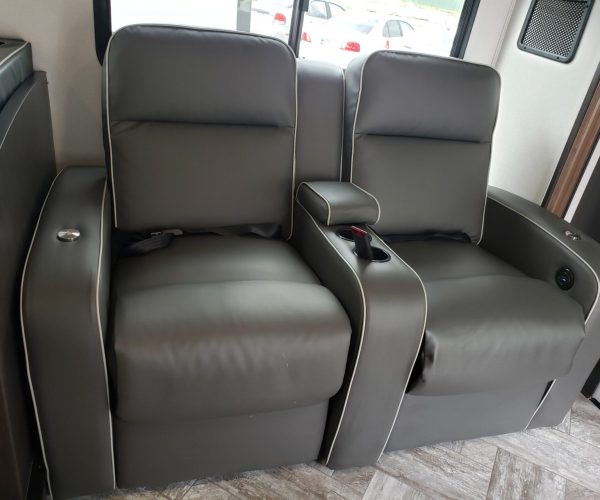 A couple of grey leather chairs in front of a window.