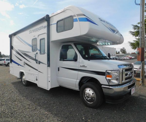 A white and blue recreational vehicle parked in the parking lot.